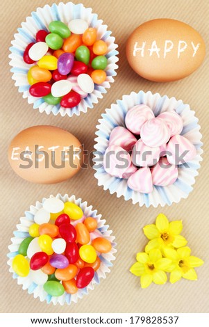 A picture of an Easter composition of eggs sweets and flowers over natural background