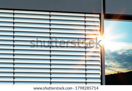 Closed external metal aluminium jalousie with reflections of sunrays  Royalty-Free Stock Photo #1798285714