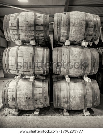 Stacks of traditional full whisky barrels, set down to mature, in a large warehouse facility