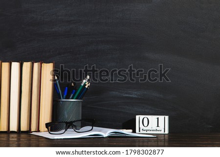 Books, calendar, notebooks, pencils, glasses and cup of coffee, against the background of a chalkboard. Concept for knowledge day. Copy space.