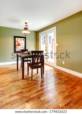 Small dining room with a hardwood floor and olive walls. Furnished with a black dining table set.