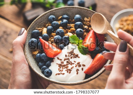 Bowl of granola with fruits and greek yogurt in female hands. Fitness food menu, dieting, clean eating concept Royalty-Free Stock Photo #1798337077