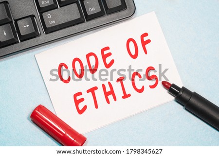 CODE OF ETHICS text on the business card written in red marker near the keyboard on a blue background