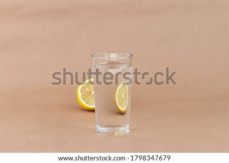 art picture of lemon behind water glass, creative reflections beige background