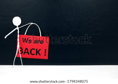 Stick man figure holding a We are Back red signage. Business and shop reopening after covid-19 pandemic concept.
