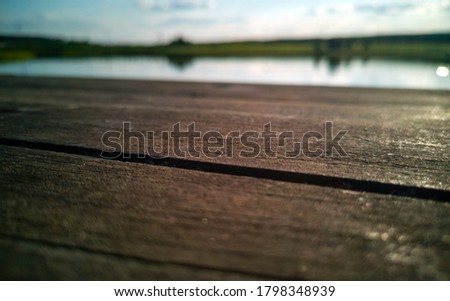Old wooden board close-up. In the background a blurred lake and sky.