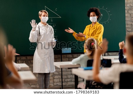 African American teacher introducing a doctor to school children who came to educate them how to take care during coronavirus epidemic.  Royalty-Free Stock Photo #1798369183