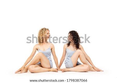 Two women in yoga pose on a white isolated background. Pair yoga class.