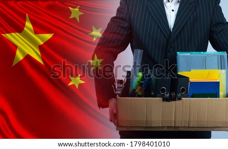 Dismissal. Unemployment in China. Unemployed next to flag of PRC. Box with office supplies in hands of a man. Concept - increase in number of unemployed. Mass dismissal in People's Republic of China.