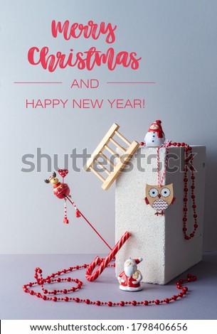 Modern minimalistic christmas composition with red color decoration keeping balance. A deer, snowman, Santa Claus, owl and christmas beads. Alternative greeting card with gray background