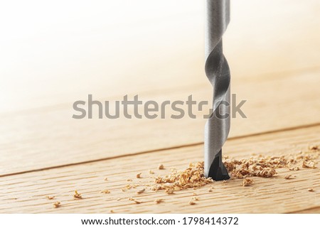 drill makes a hole in the wooden oak table with wood