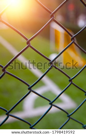 Astroturf or synthetic grass soccer field with blurred corner lines, soccer ball and goal post behind the metal fence Royalty-Free Stock Photo #1798419592