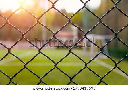 Astroturf or synthetic grass soccer field with blurred white lines and goal post behind the metal fence.  Royalty-Free Stock Photo #1798419595