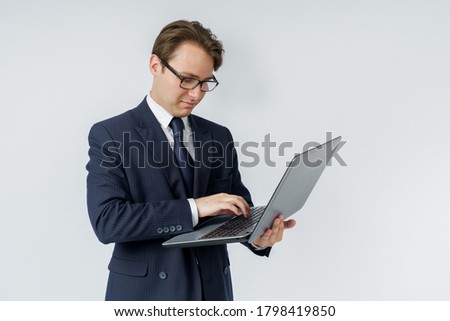 A businessman is holding a laptop in his hands, is typing with one hand. White background. Business and finance concept