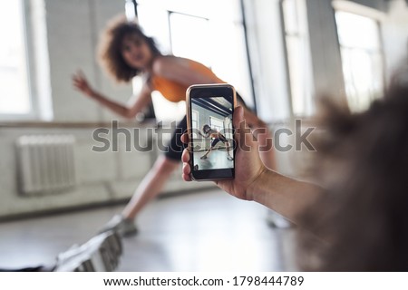 Cropped photo of man using mobile phone and making video of his female friend during rehearsing dance moves