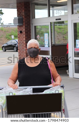 Lady  with a mask on in a parking lot in front of a store