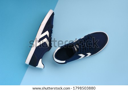 A pair of navy blue sneakers lying on a dark and light blue background. Minimal photo