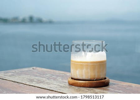 Dirty Coffee - A glass of espresso shot mixed with cold fresh milk on sea view background and copy space.