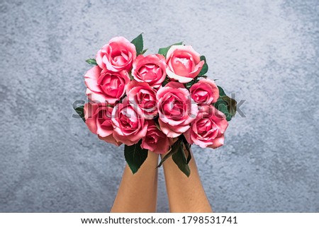 female hands hold romantic bouquet of tender pink roses on gray concrete background Holiday floral card Birthday, Wedding, Happy Valentine's, Mother's, Teacher's day creative concept Top view Flat lay