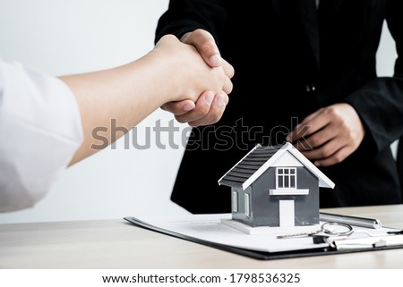 Businessmen and brokers real estate agents shake hands after completing negotiations to buy houses insurance and sign contracts. Home insurance concept.
