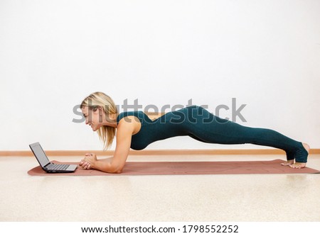a woman with blond hair does online training stands in front of a laptop and smiles