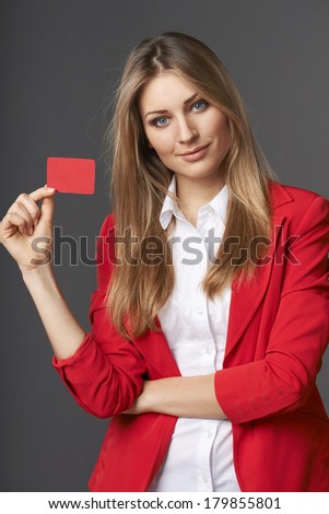 Beautiful smiling business woman showing red card in hand, over gray background