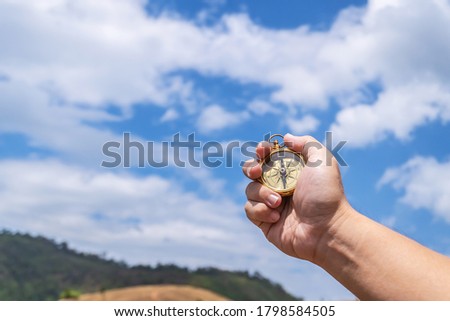 Male traveler man hand with compass on background of meadow mountains in summer