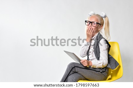 Cute little girl child covered her mouth in surprise when she saw the message in tablet computer