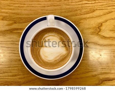 Coffee art heart shape using milk to create in coffee on wood texture surface of table indoor round plate with navy blue trim in Thailand nobody picture