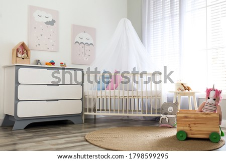 Baby room interior with cute posters, chest of drawers and comfortable crib