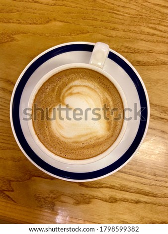 Coffee art heart shape using milk to create in coffee on wood texture surface of table indoor round plate with navy blue trim in Thailand nobody picture