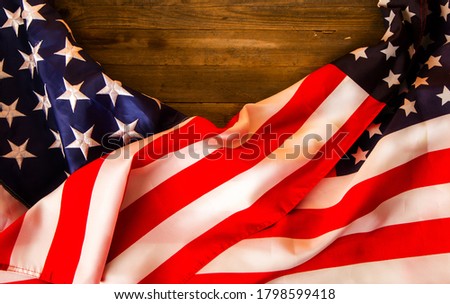 Two Stars and Stripes of the United States of America stacked on an old wooden background with a place for an inscription