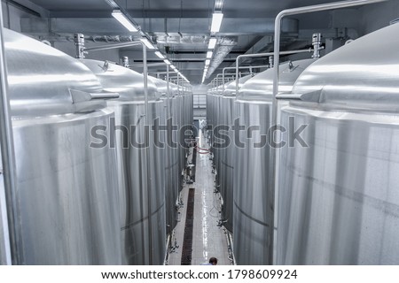 Row of tanks in brewery. Fermentation in brewery tanks with beer for brewing. Modern beer factory. Big steel tanks for storage. Camera view from top to bottom Royalty-Free Stock Photo #1798609924