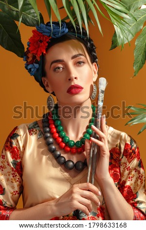 The girl brunette in the ethnic image of Mexican artist Frida Kahlo. Studio shooting, yellow background.