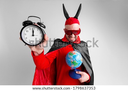 Man in halloween costume posing with globe and watches in his hands over white background.