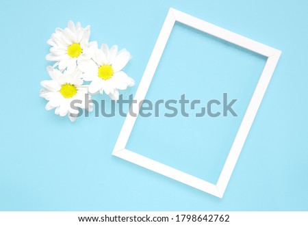 Mockup square white frame with white flowers on blue background. View top. Messege or invitation card mock-up concept. flower layut. copy space for text.