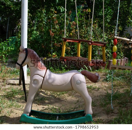 Toy horse and baby swing in the garden