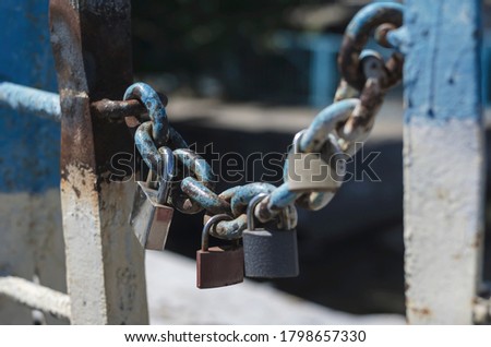 Various padlocks hang from an old chain. Wedding padlocks chained to the city bridge. Symbol of love and old wedding tradition. Old rusty sweetheart locks.