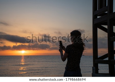 A woman taking pictures with her home on the beach