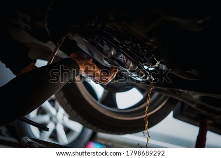 Car mechanic drain the old automatic transmission fluid (ATF) or gear oil at car garage for changing the oil in a gear box of car engine Royalty-Free Stock Photo #1798689292