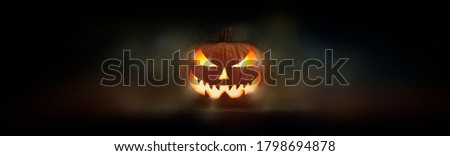 One spooky evil halloween lantern, Jack O Lantern, with glowing eyes and face on a dark background.