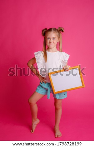 Portrait of a girl holding an empty frame, surprised place for text Studio on a pink background
