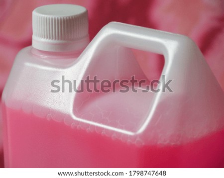 Pink chemical liquid in a white plastic container on pink tye dye fabric background