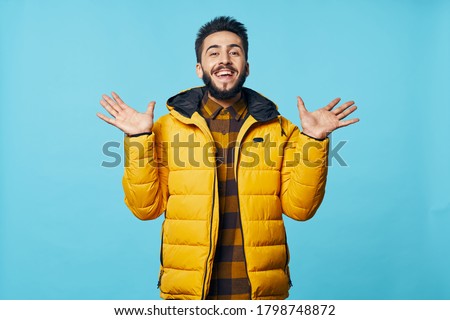 Cheerful man yellow jacket gesture with hands emotions blue background