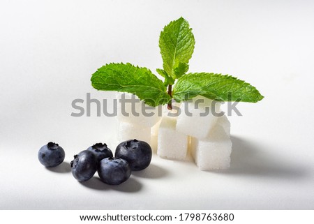 Refined sugar with mint and blueberries on a white background for isolation. Set of sugar sprigs of mint and blueberries.