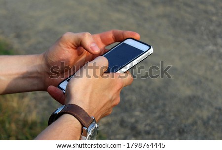 Man holding a smartphone outdoor. Grey background. 