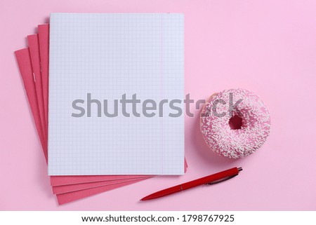 School notebooks and pink donut on colored background, top view