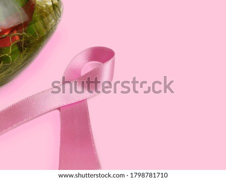 Pink ribbon breast cancer awareness symbol with lucky bamboo plant on pink background with space for text