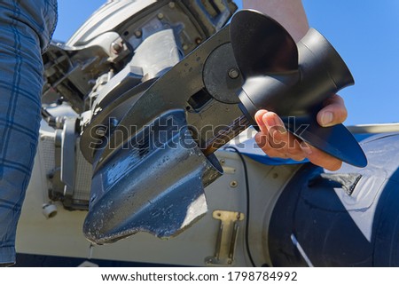 man changing propeller on outboard motor. Repairing outboard motor for boat, replacing screw. Royalty-Free Stock Photo #1798784992
