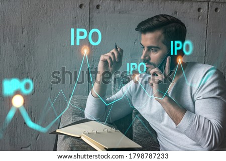 Handsome analyst in casual long sleeve talking phone, taking notes at office workplace try to analyze IPO project. Double exposure. Initial public offering hologram. Royalty-Free Stock Photo #1798787233
